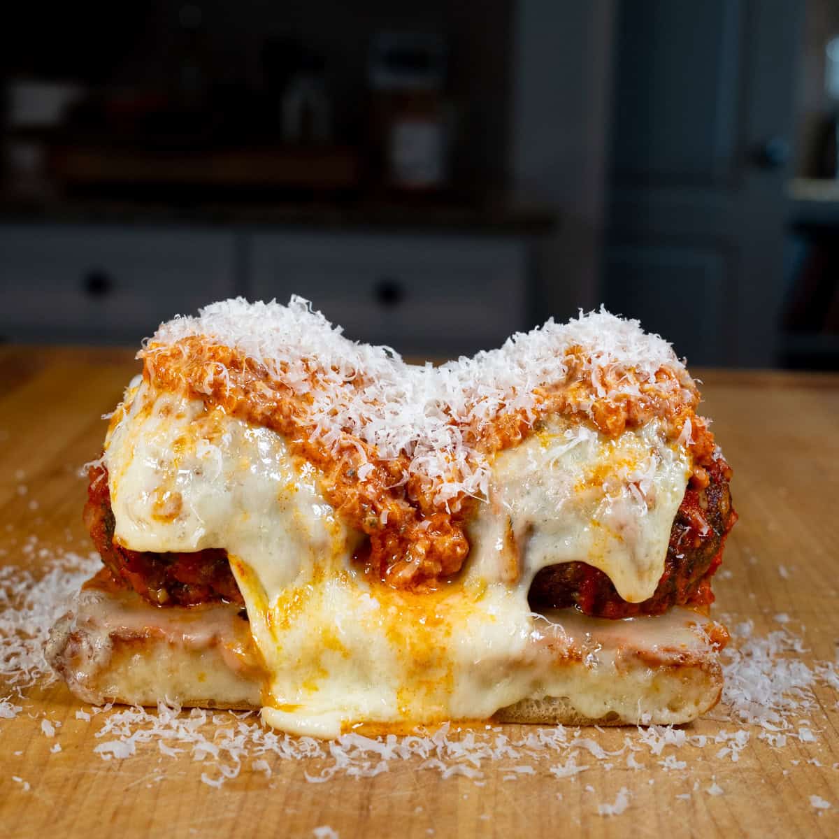 Meatball Sub topped with melted provolone cheese, marinara sauce, and grated parmesan cheese