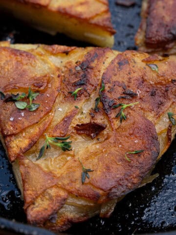 pommes anna potatoes seared in a cast iron skillet