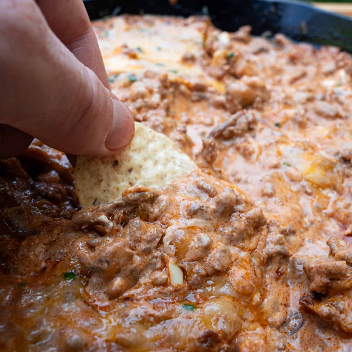 Dipping into chili cheese dip with tortilla chip