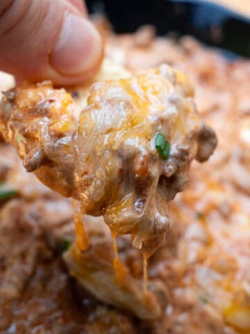 Dipping tortilla chip into chili cheese dip