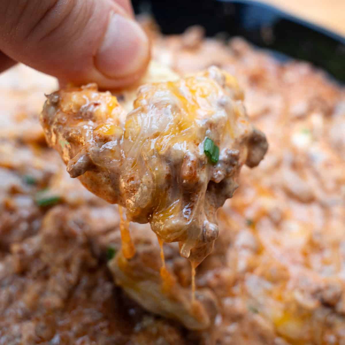 Dipping tortilla chip into chili cheese dip