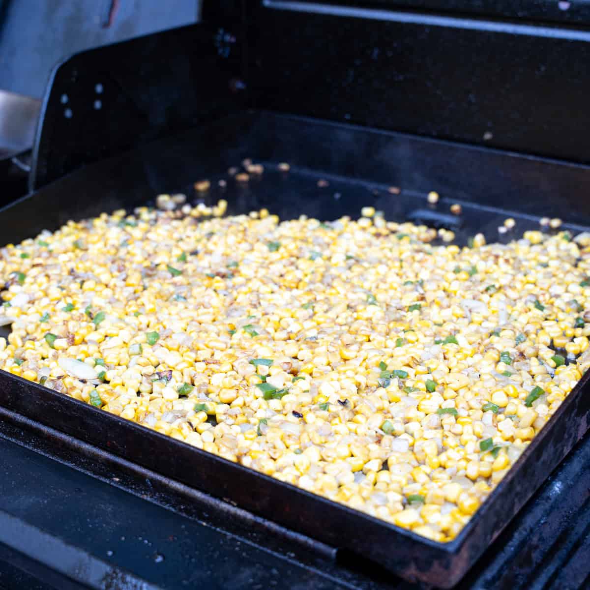 Charring corn, jalapeños, and onions on the griddle