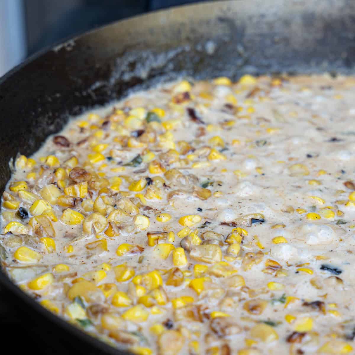 Simmering liquids in the skillet with corn and vegetables