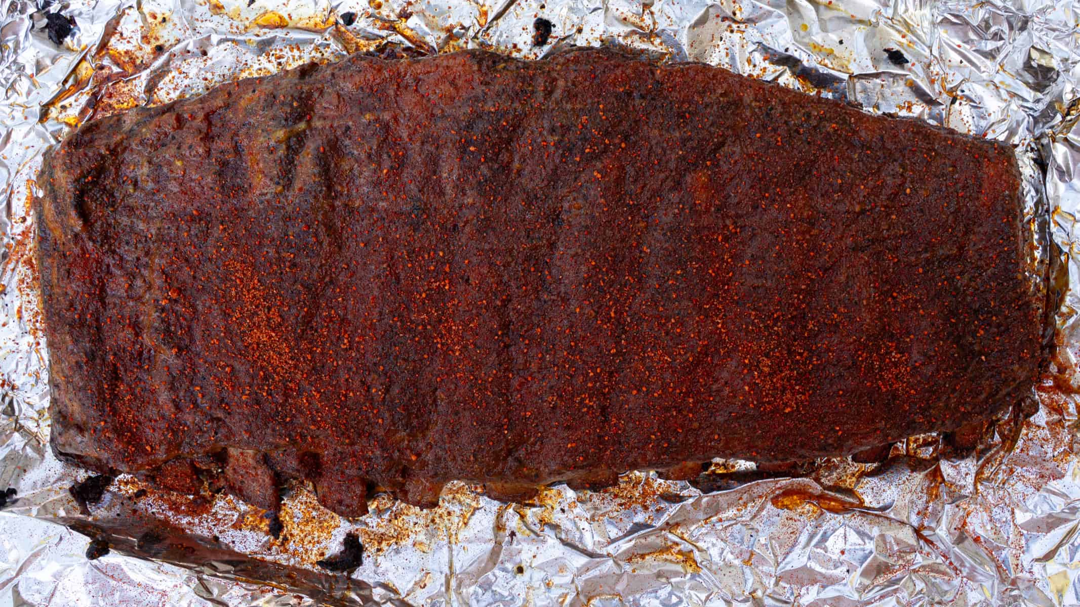 Ribs have been unwrapped, sauced, and re-seasoned for the final phase of the cook