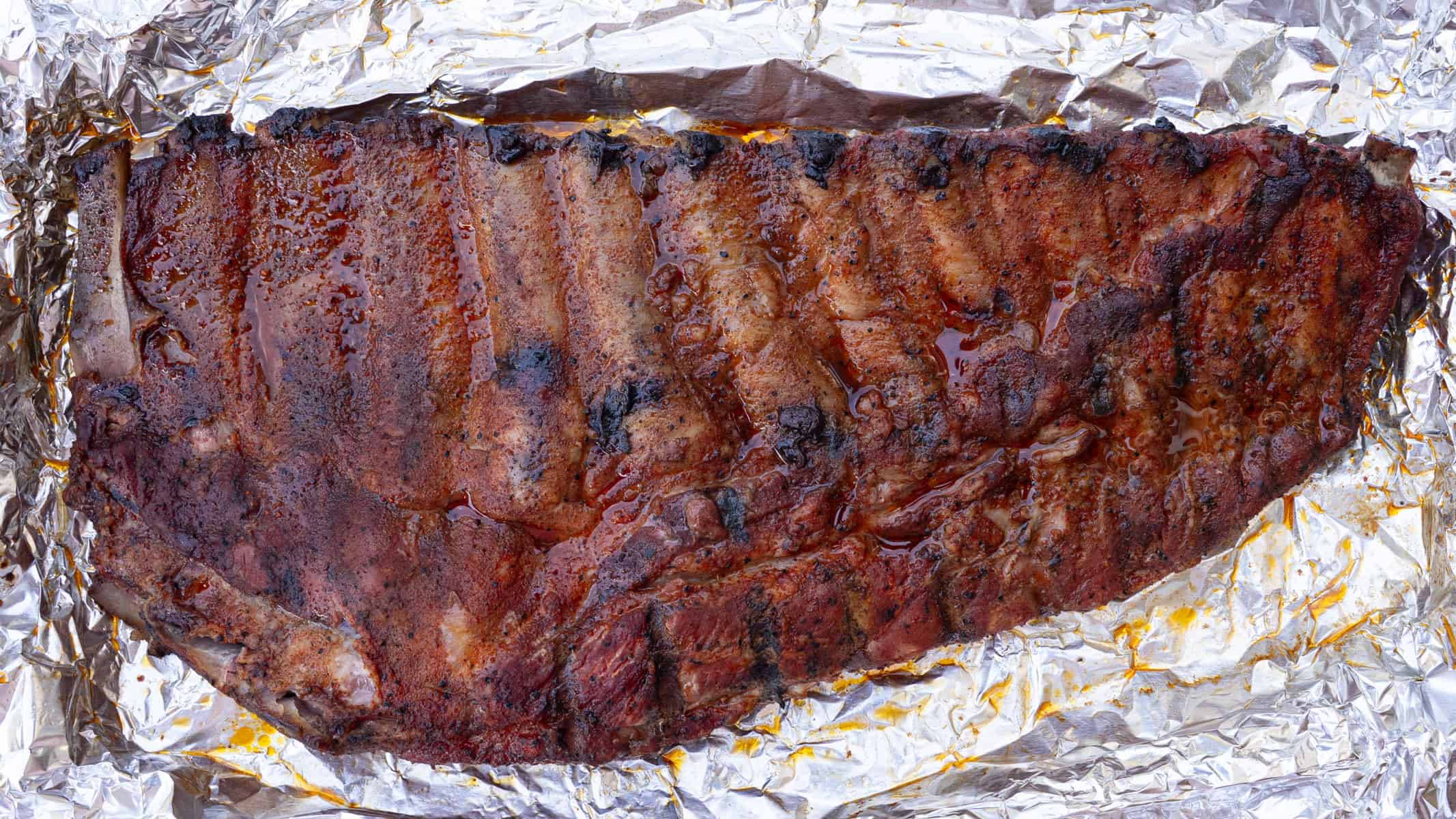 Placing the ribs meat side down with liquid before being wrapped