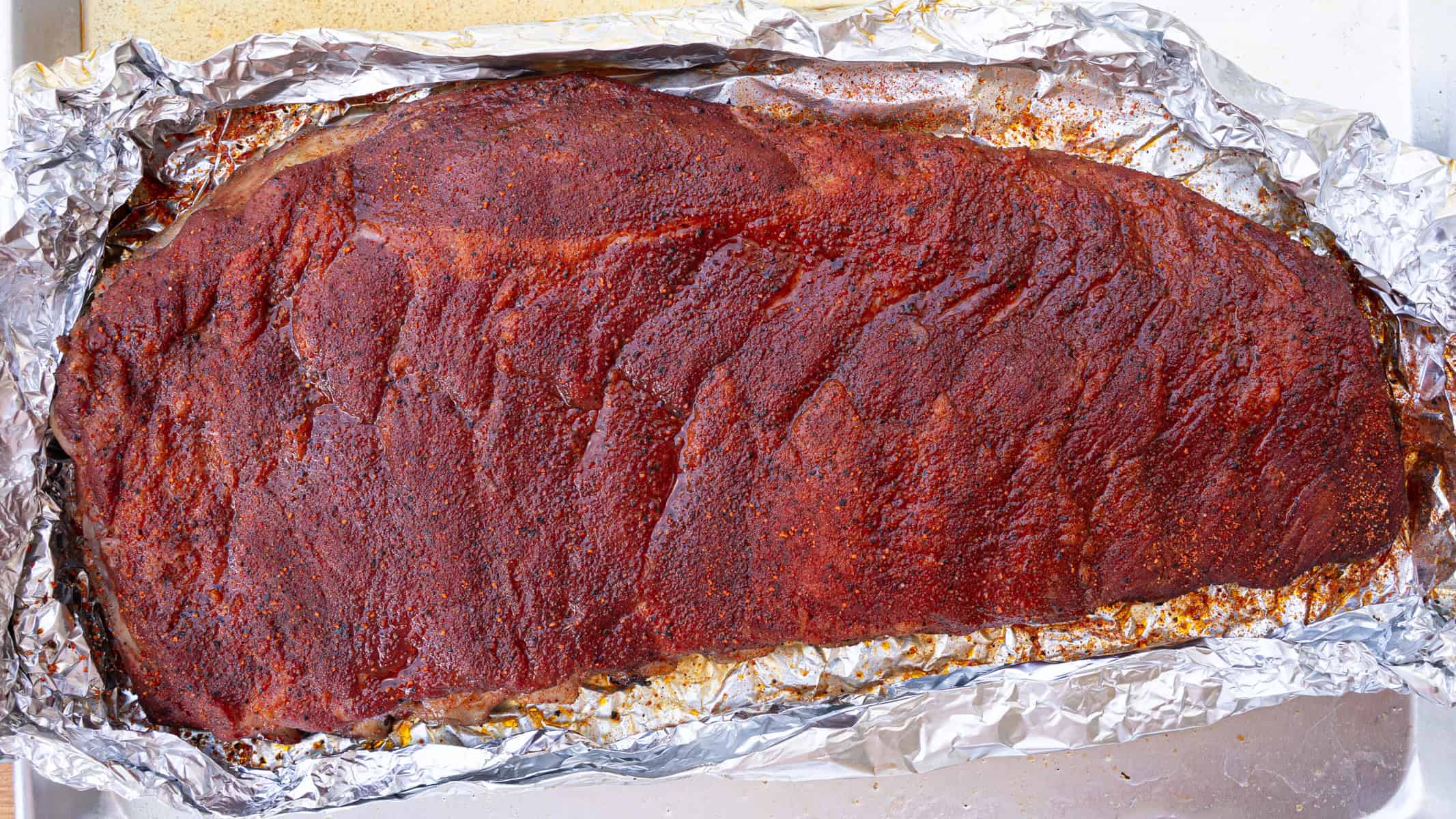 Unwrapped ribs that have been freshly seasoned after hours one the smoker