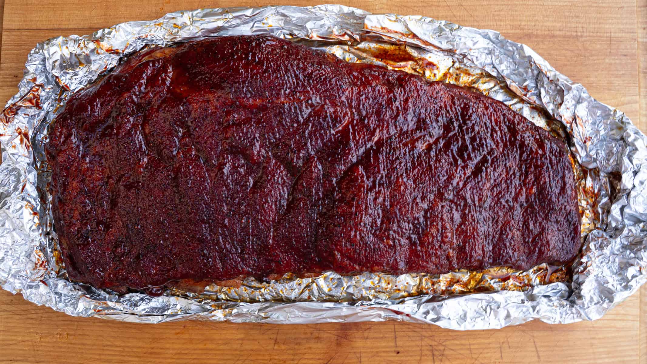 Smoked Spare Ribs that have just been glazed with BBQ Sauce and are ready to go back on the smoker