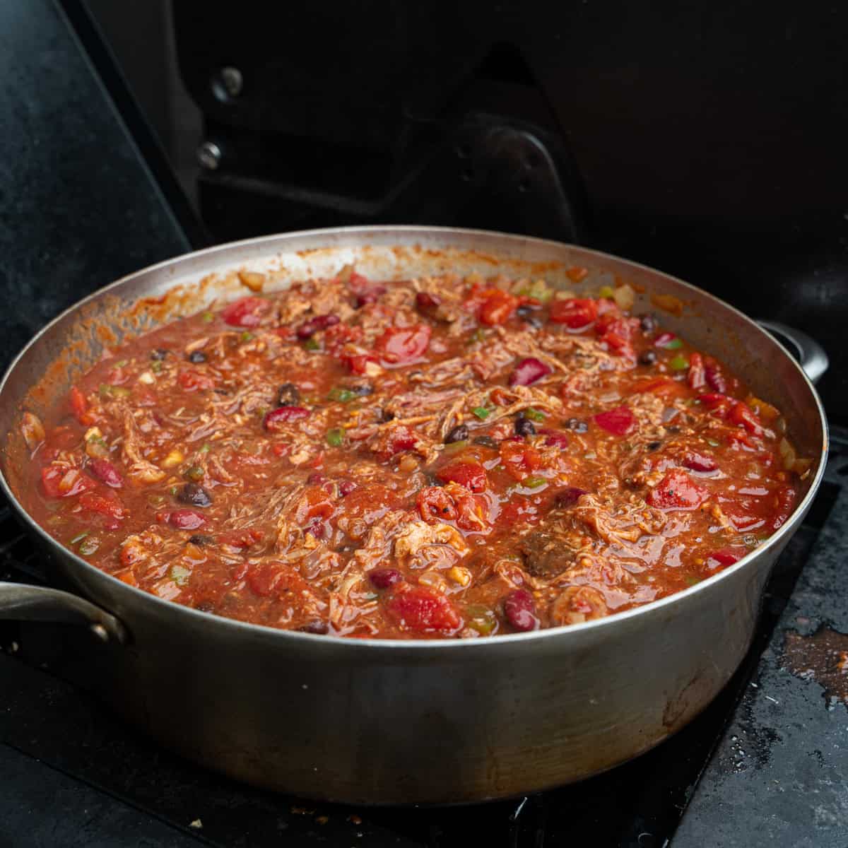 finishing chili on the heat source after adding pork