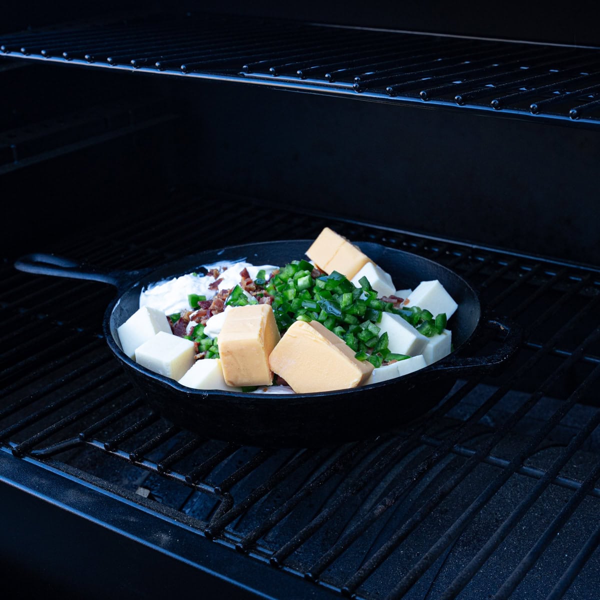 Jalapeño Popper Dip ingredients placed in a skillet on the smoker to cook