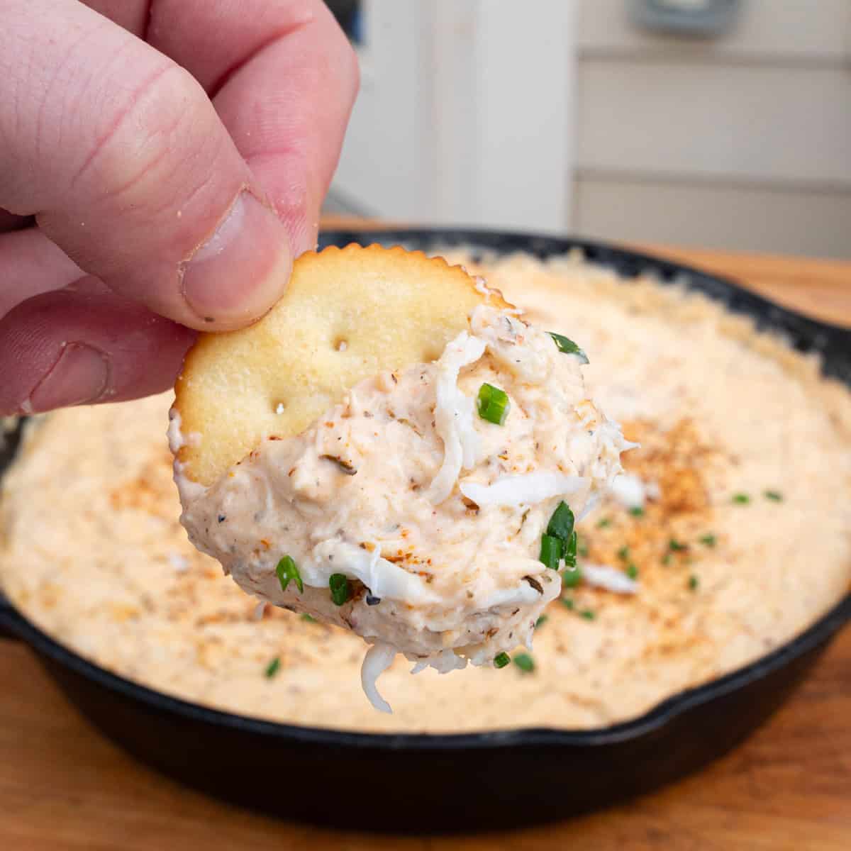 Cajun crab dip being scooped with a butter cracker