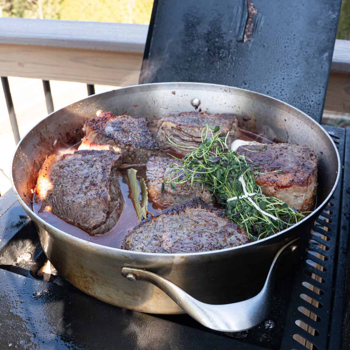 adding the liquids and aromatics into a large skillet with the bottom round roast