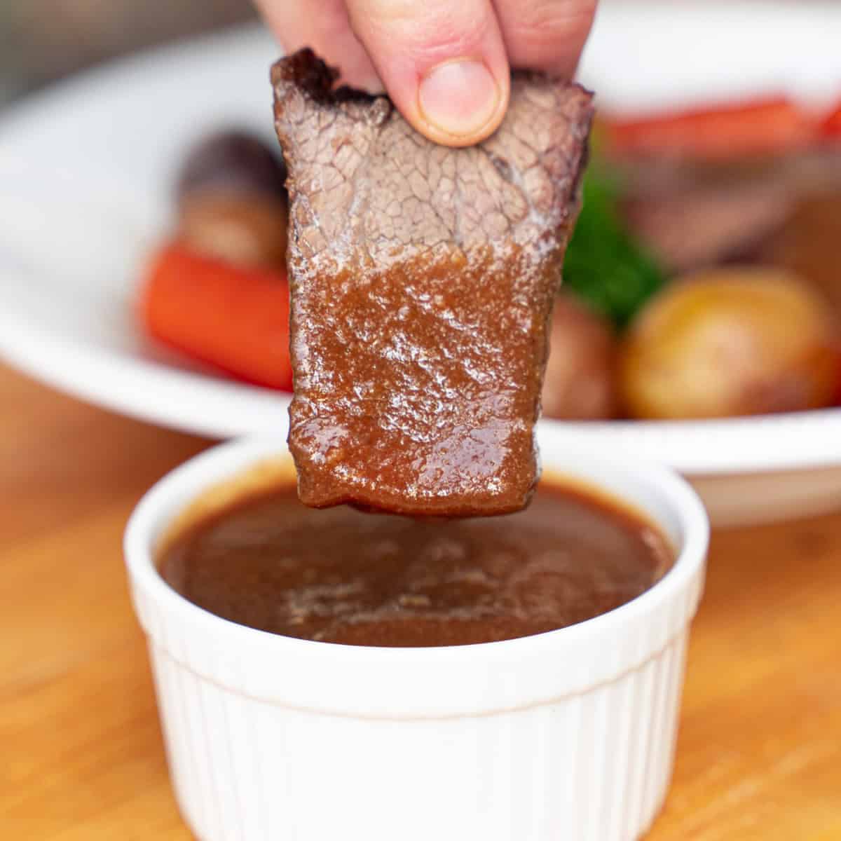 Dipping a slice go bottom round roast into brown gravy