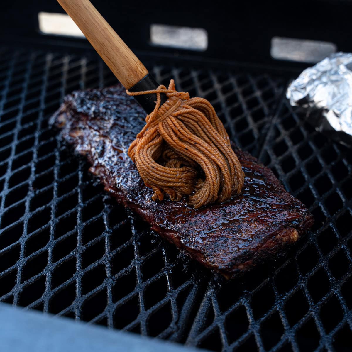 Direct Heat Ribs with a fresh coat of mop sauce being applied