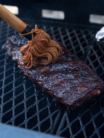 Direct Heat Ribs with a fresh coat of mop sauce being applied