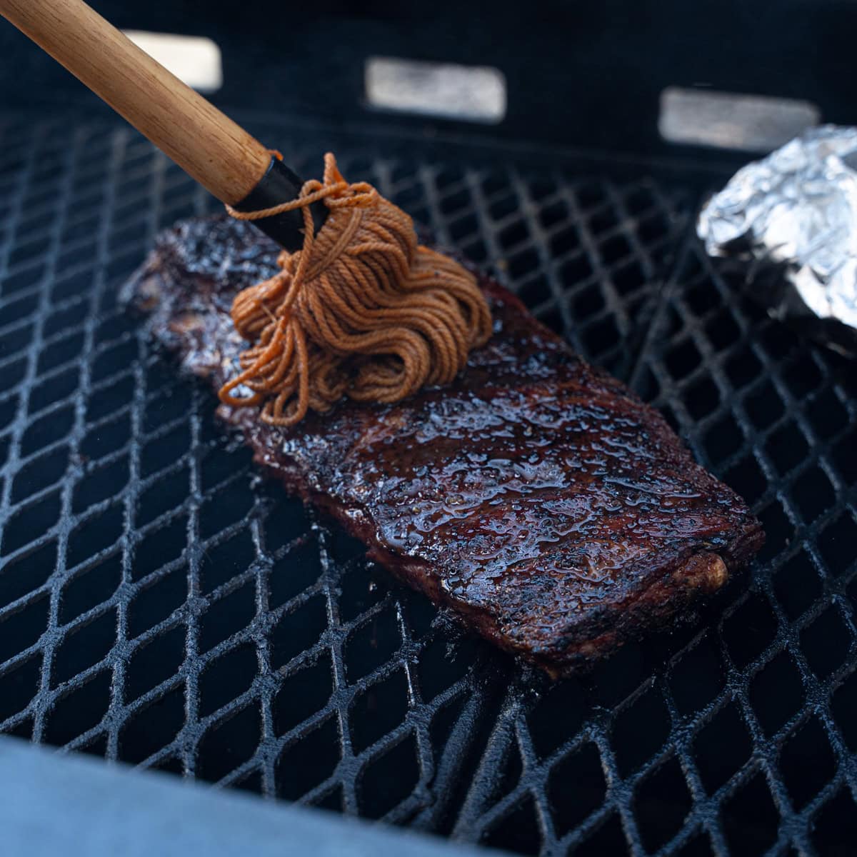 Direct Heat Ribs with a fresh coat of mop sauce being applied
