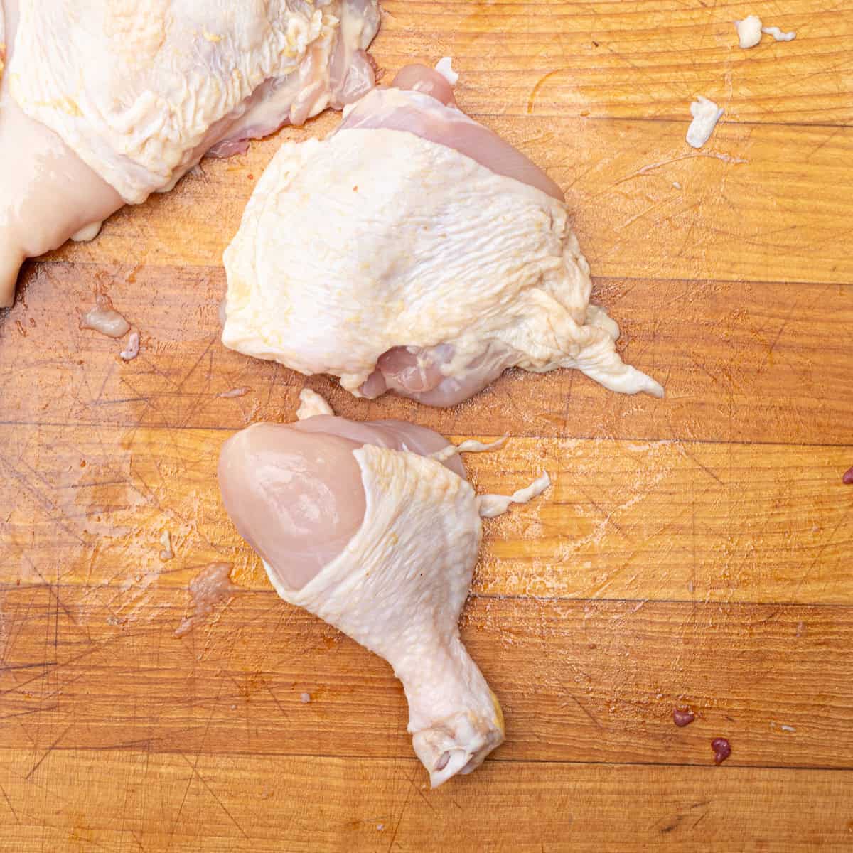 A raw chicken thigh and drumstick sliced from a whole chicken