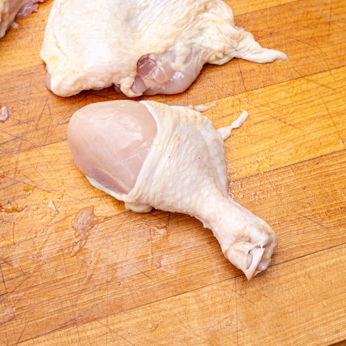 A raw chicken drumstick sliced from a whole chicken