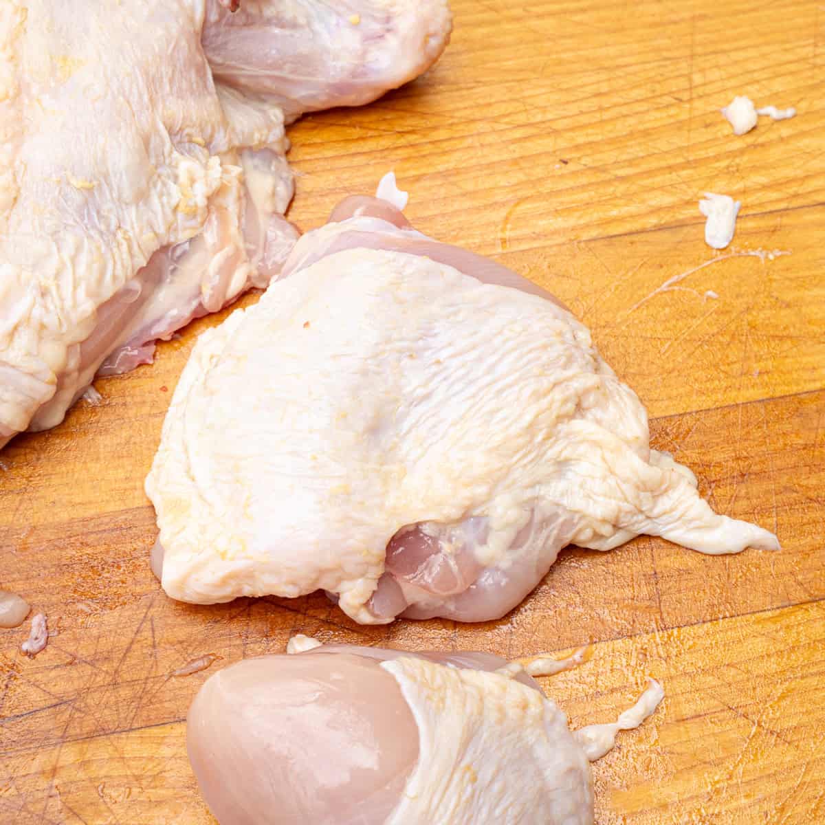 A raw chicken thigh sliced from a whole chicken