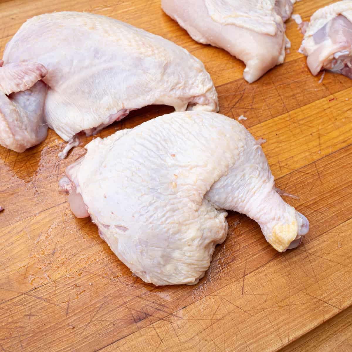 A raw chicken quarter sliced from a whole chicken
