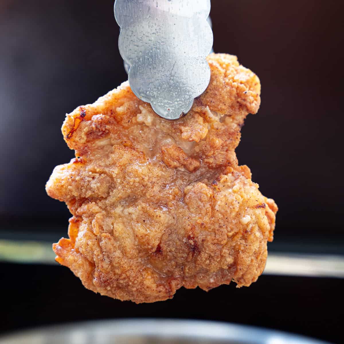 A fried chicken thigh just pulled out of the skillet and ready to be served