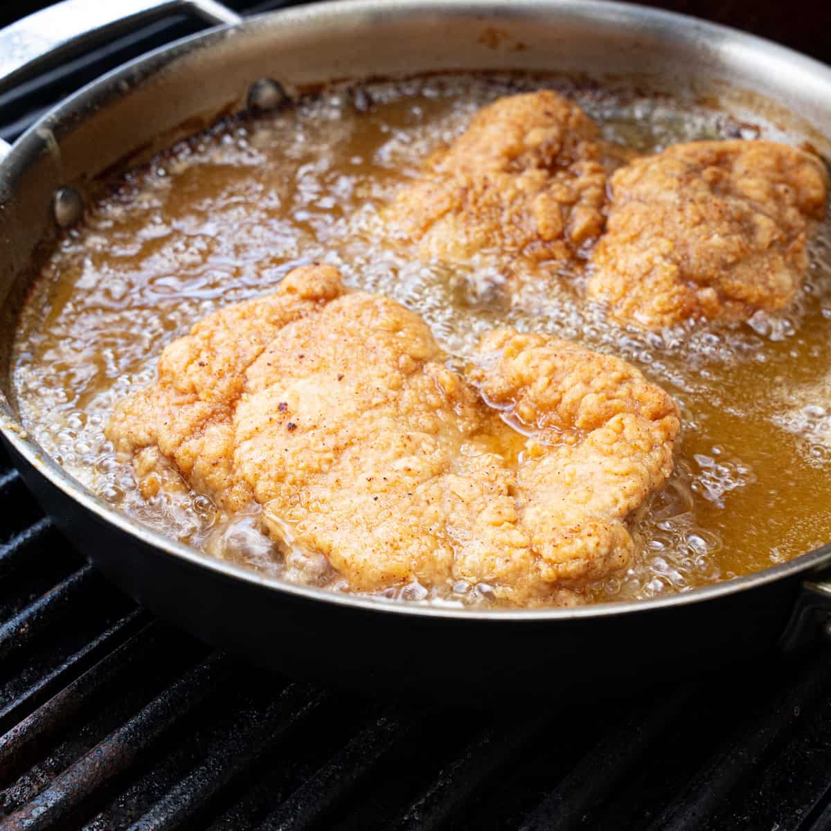 Chicken turning golden brown while frying in a skillet