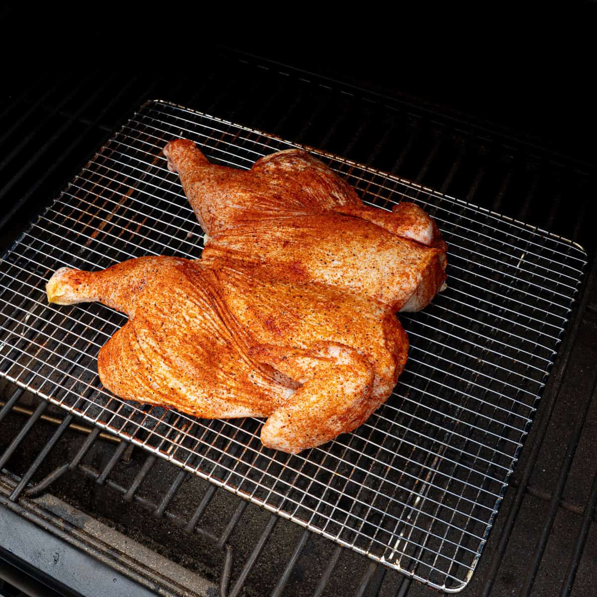 Spatchcock chicken just placed on a pellet grill to smoke