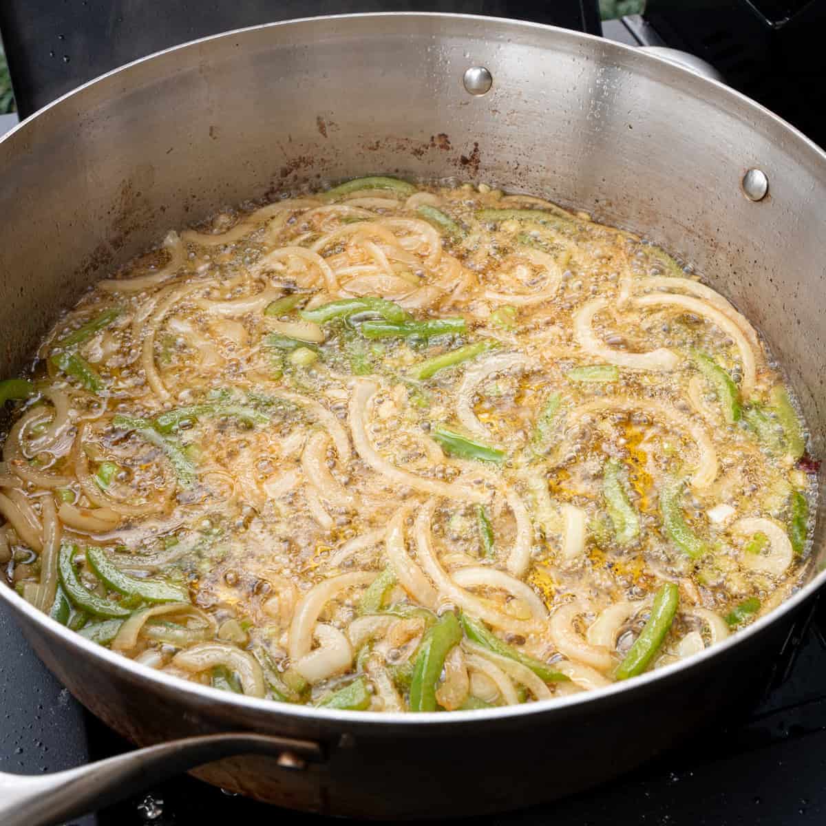 Sautéing the onions and bell peppers in oil to make the base of the chicken gravy