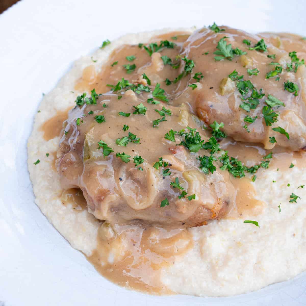 Smothered chicken with onions served over cheese grits