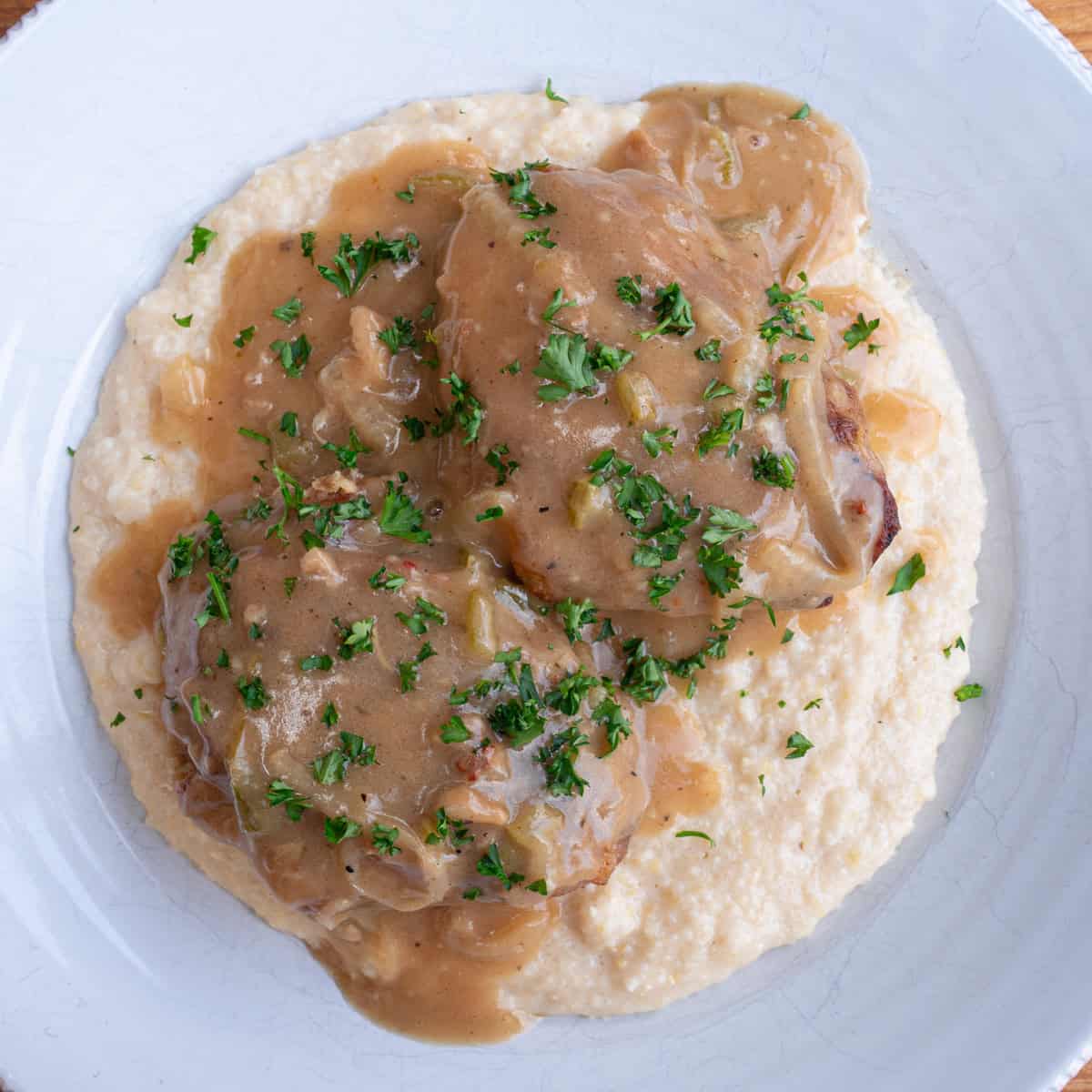 Smothered chicken with onions served over cheese grits