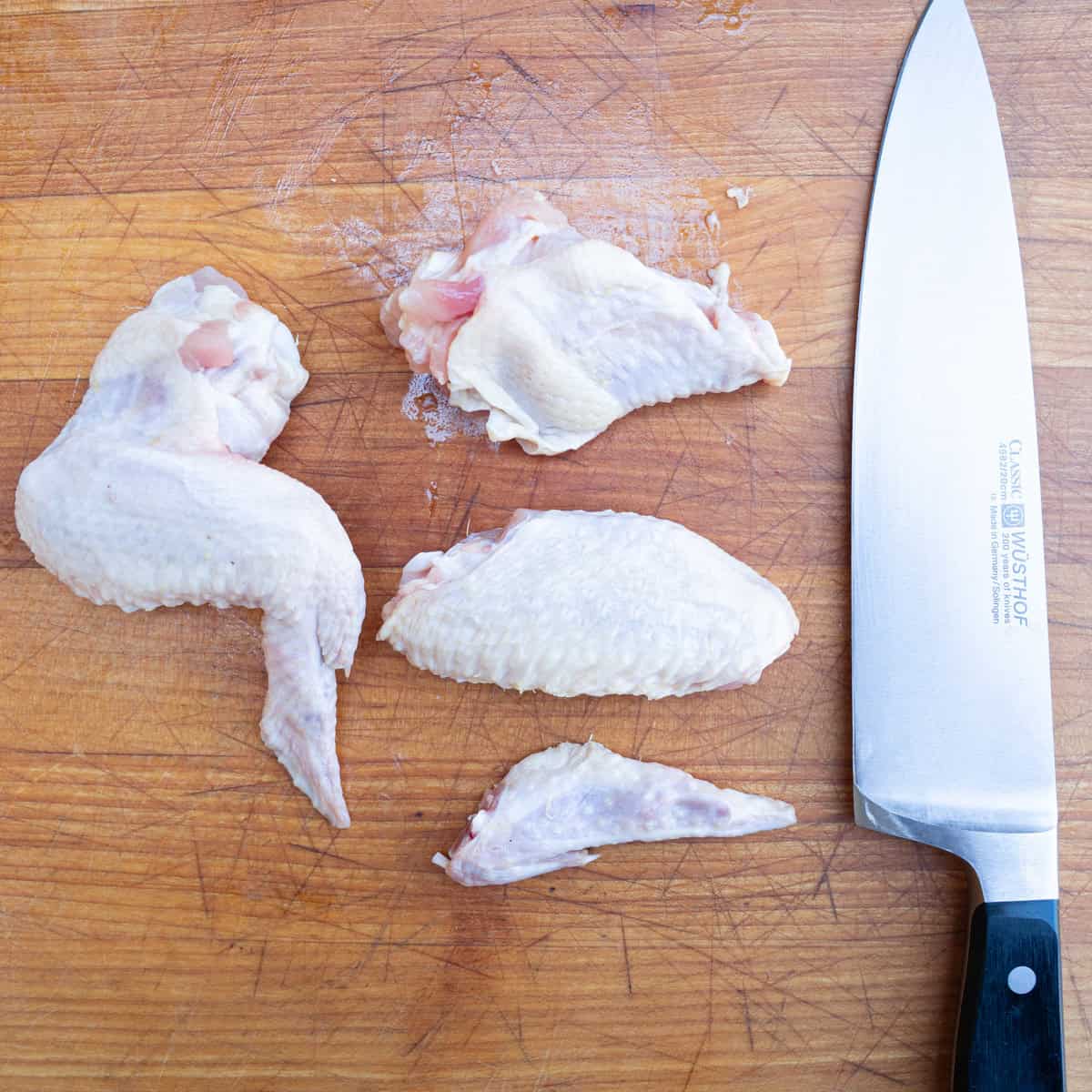 Fully trimmed chicken wings next to a whole chicken wing