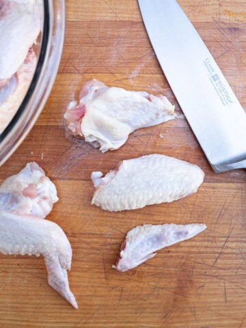 Fully trimmed chicken wings next to a whole chicken wing