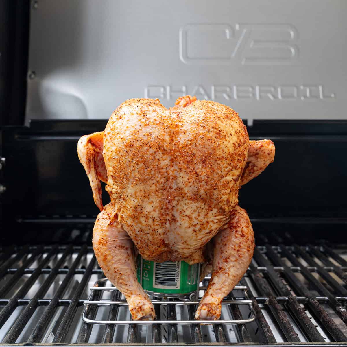Seasoned beer can chicken just placed on the grill to cook