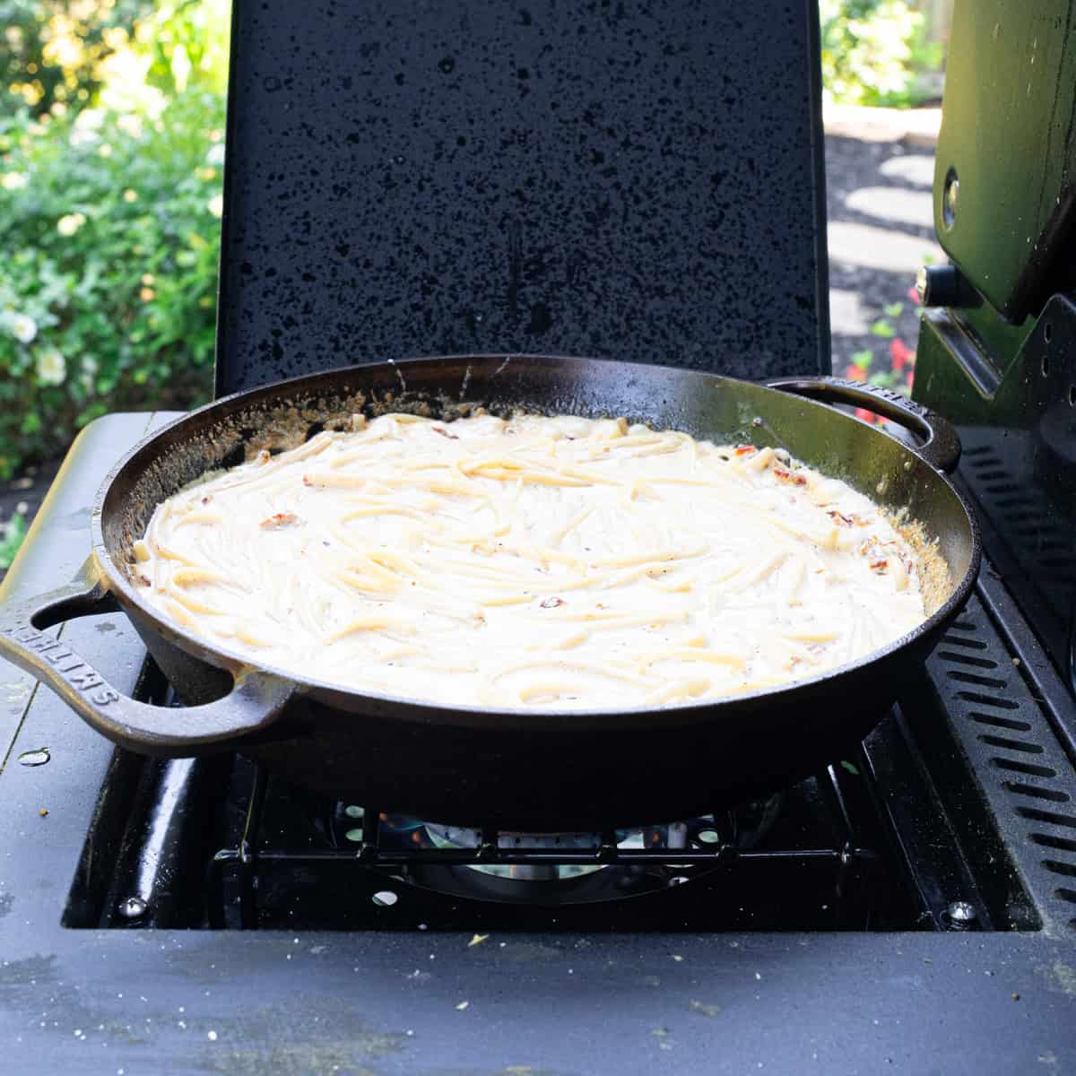 Letting the pasta noodles soak in the cajun Alfredo sauce in a skillet